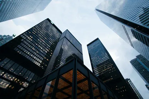 Tours de bureaux vues en contre-plongée, sous un ciel bleu nuageux.